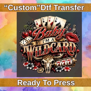 May include: A Custom Dtf Transfer Ready To Press graphic featuring the text Baby I'm A Wildcard. The design includes playing cards, dice, cherries, a pair of red lips, a leopard print cow skull, a slot machine showing 777, and poker chips.