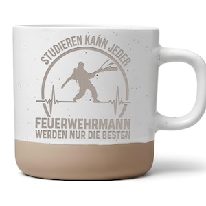 Könnte beinhalten: Ein weißer Keramikbecher mit Sprenkeloptik und beigem Boden. Auf der Vorderseite befindet sich eine graue Grafik mit der Silhouette eines Feuerwehrmanns, einer Herzschlaglinie und dem Text: STUDIEREN KANN JEDER FEUERWEHRMANN WERDEN NUR DIE BESTEN.