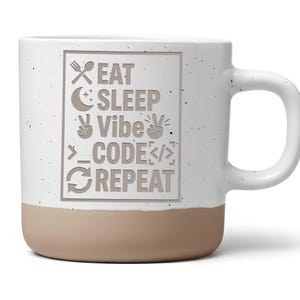 Könnte beinhalten: Ein weißer Keramikbecher mit gesprenkelter Oberfläche und einem beigen Boden. Auf der Vorderseite befindet sich eine rechteckige Grafik mit dem Text EAT SLEEP Vibe CODE REPEAT sowie Symbolen für Gabel, Löffel, Mond, Friedenszeichen und Code.