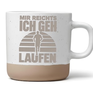 Könnte beinhalten: Ein weißer Keramikbecher mit Sprenkeloptik und beigefarbenem Boden. Auf der Vorderseite befindet sich eine Grafik eines Läufers in einem Sonnenuntergangskreis sowie der deutsche Schriftzug "MIR REICHTS ICH GEH LAUFEN" in großen, grauen Buchstaben.