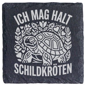 Könnte beinhalten: Ein quadratischer Untersetzer aus schwarzem Schiefer mit rauer, strukturierter Kante. Die Oberfläche zeigt eine weiße Gravur einer Schildkröte, umgeben von stilisierten Blättern und Herzen, sowie den weißen Schriftzug "ICH MAG HALT SCHILDKRÖTEN".