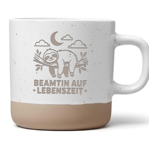Könnte beinhalten: Weißer Keramikbecher mit beigefarbenem Boden und großem Henkel. Der Becher zeigt ein Design eines schlafenden Faultiers auf einem Ast, mit Mond und Wolken. Der Text "BEAMTIN AUF + LEBENSZEIT +" befindet sich darunter.