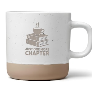 Könnte beinhalten: Weißer Keramikbecher mit beigefarbenem Boden und großem Henkel. Der Becher zeigt eine Bücherstapel und eine Kaffeetasse-Grafik mit dem Text "JUST ONE MORE CHAPTER" in Grau.