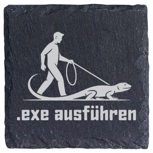Könnte beinhalten: Ein quadratischer Untersetzer aus schwarzem Schiefer mit rauer, strukturierter Kante. Die Oberfläche zeigt eine weiße Grafik einer Person, die eine Eidechse an der Leine führt, mit dem Text .exe ausführen in weißer, fetter Schrift darunter.