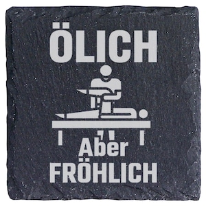 Könnte beinhalten: Ein quadratischer Untersetzer aus schwarzem Schiefer mit rauer, strukturierter Kante. Die Oberfläche zeigt eine weiße Grafik einer Person, die eine Massage an einer auf einem Tisch liegenden Person durchführt. Der Text "ÖLICH" steht oben und "Aber FRÖHLICH" unten.