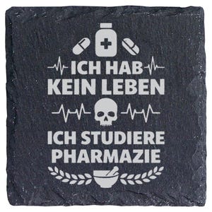 Könnte beinhalten: Ein quadratischer Untersetzer aus schwarzem Schiefer mit weißer Gravur eines Medikamentenfläschchens, Pillen, eines Totenkopfes sowie Mörser und Stößel. Der Text lautet ICH HAB KEIN LEBEN ICH STUDIERE PHARMAZIE, ergänzt durch EKG-Herzlinien.