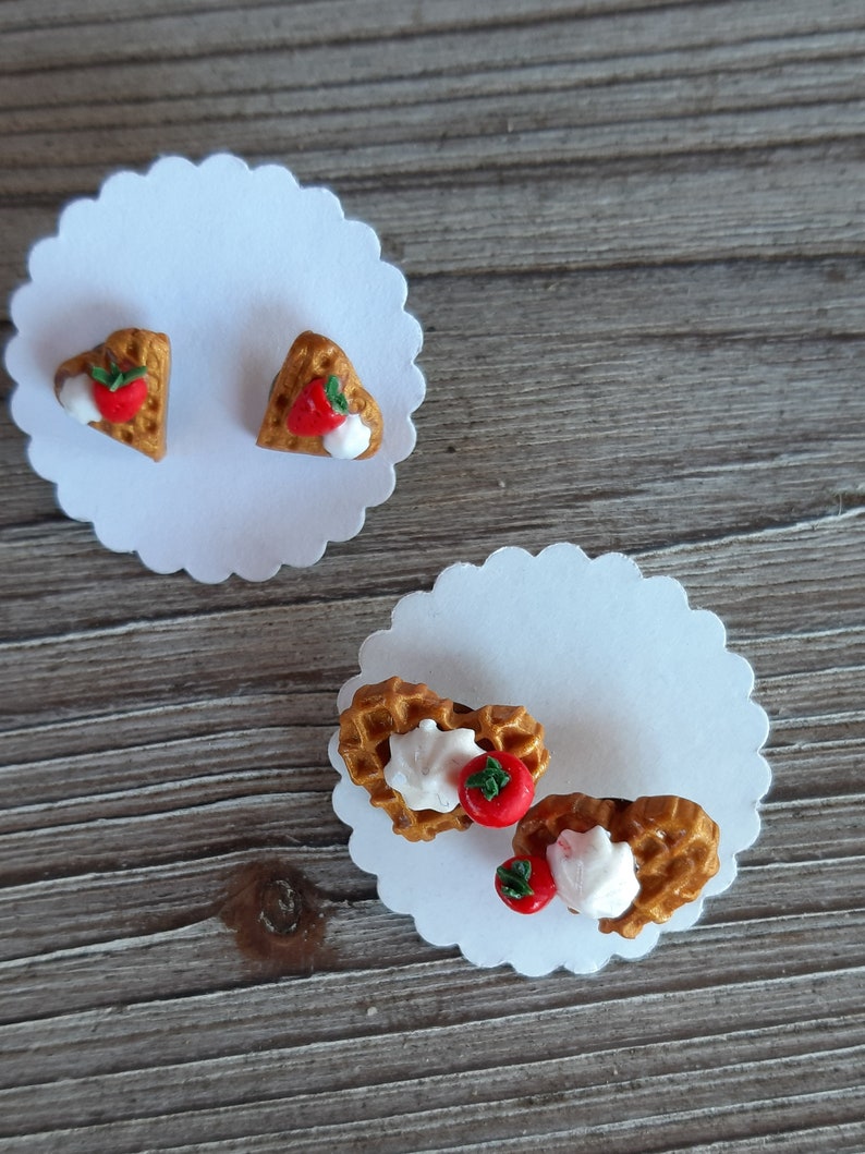 Puede incluir: Pendientes de gofres en forma de coraz&oacute;n con fresas y crema batida, presentados sobre tarjetas blancas festoneadas. Los pendientes son de color marr&oacute;n dorado y descansan sobre una superficie de madera. Cada pendiente es un gofre en miniatura.
