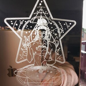 May include: A copper-colored, rectangular ornament with a laser-etched design. The design features a figure wearing headphones, making a peace sign, and surrounded by geometric shapes and a star. An Apple logo is visible.