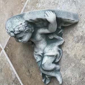 May include: A white ceramic mug with a black handle and the text "But First, Coffee" in a bold, black font. The mug is filled with a dark liquid, likely coffee, and sits on a light-colored surface.