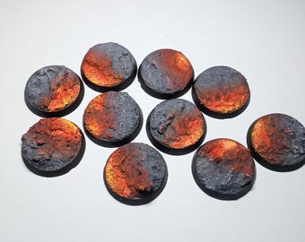 May include: A collection of eleven round, textured bases for miniature figures. Each base features a color scheme of gray and orange, resembling a volcanic or fiery landscape. The bases are ideal for tabletop gaming.