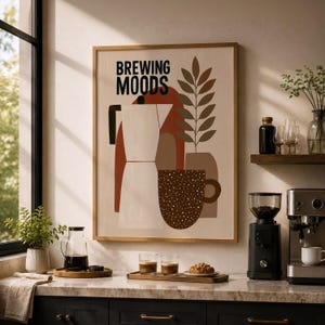 Könnte beinhalten: Ein rechteckiges Wandbild in einem hellen Holzrahmen mit dem schwarzen Schriftzug BREWING MOODS. Das Grafikdesign zeigt eine weiße Mokkakanne, eine braun gesprenkelte Kaffeetasse und eine stilisierte grüne Pflanze auf cremefarbenem Grund.