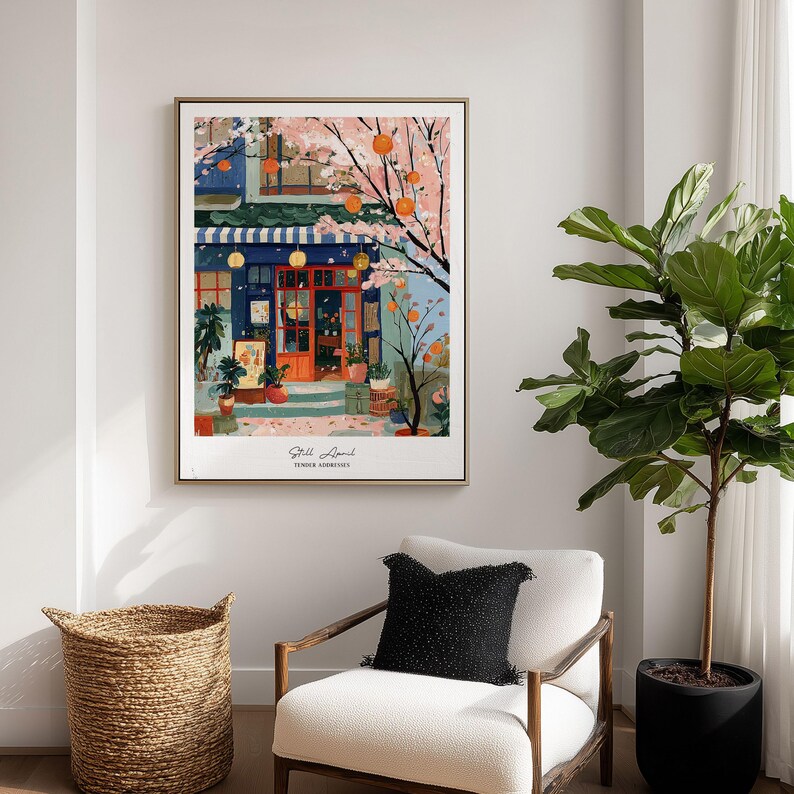 May include: A framed art print depicting a colorful cafe scene with a blue facade, orange door, and striped awning. The artwork features a blossoming tree with orange fruit and the text "Still April, Tender Memories."