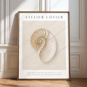 Può includere: Una stampa artistica incorniciata con un'illustrazione di una conchiglia di nautilo centrata su uno sfondo beige con un motivo a vortice. Il testo ATELIER CÔTIER appare in alto e una citazione in corsivo è stampata sul bordo bianco inferiore.