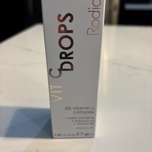 May include: A white rectangular box of Rodial Vit C Drops. The front features the text Rodial Vit C Drops, 6% vitamin c complex, beta-carotene, babassu oil, vitamin B5, and 1.01 US fl. oz. 30ml. The top edge of the packaging is bright orange.