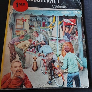 May include: A vintage book cover with the title "Hobbycraft Cyclopedia" and a red price tag that says "100". The cover features an illustration of a hobby shop with people browsing and buying items. The shop window displays signs that say "Bill and Dot's Hobby Shop" and "It's Here! New Arrivals!"