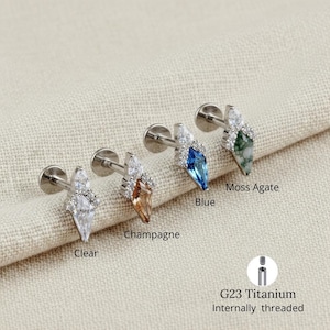 Op de afbeelding: Vier G23 titanium intern geschroefde oor piercings. Elke oorbel heeft een marquise-vormige edelsteen in helder, champagne, blauw en mosagaat. De oorbellen zijn versierd met kleine, heldere accentstenen.