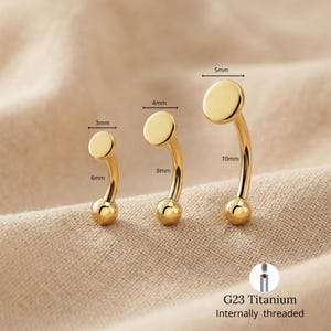 May include: Three gold-coloured curved eyebrow rings with measurements. The smallest ring has a 3mm disc, 6mm length. The middle ring has a 4mm disc, 8mm length. The largest ring has a 5mm disc, 10mm length. The rings are G23 Titanium, internally threaded.