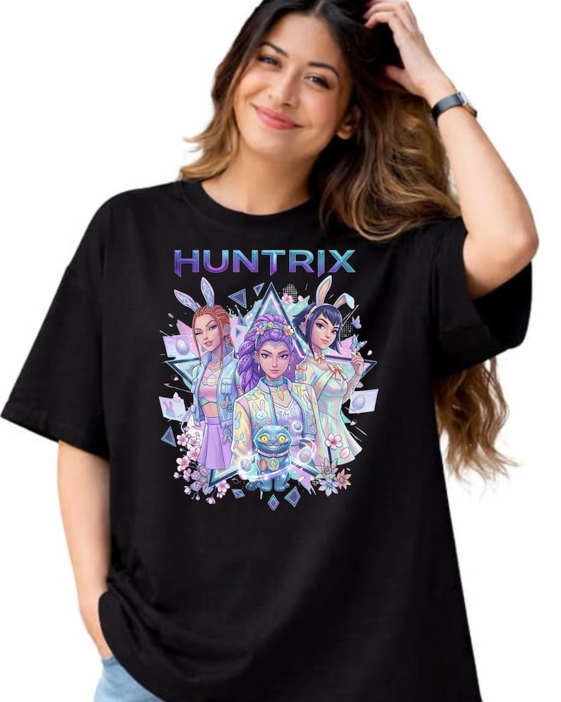 May include: Black t-shirt with the word "HUNTRIX" in a gradient colour scheme above a graphic of three anime-style characters wearing bunny ears. The graphic includes floral and geometric elements.