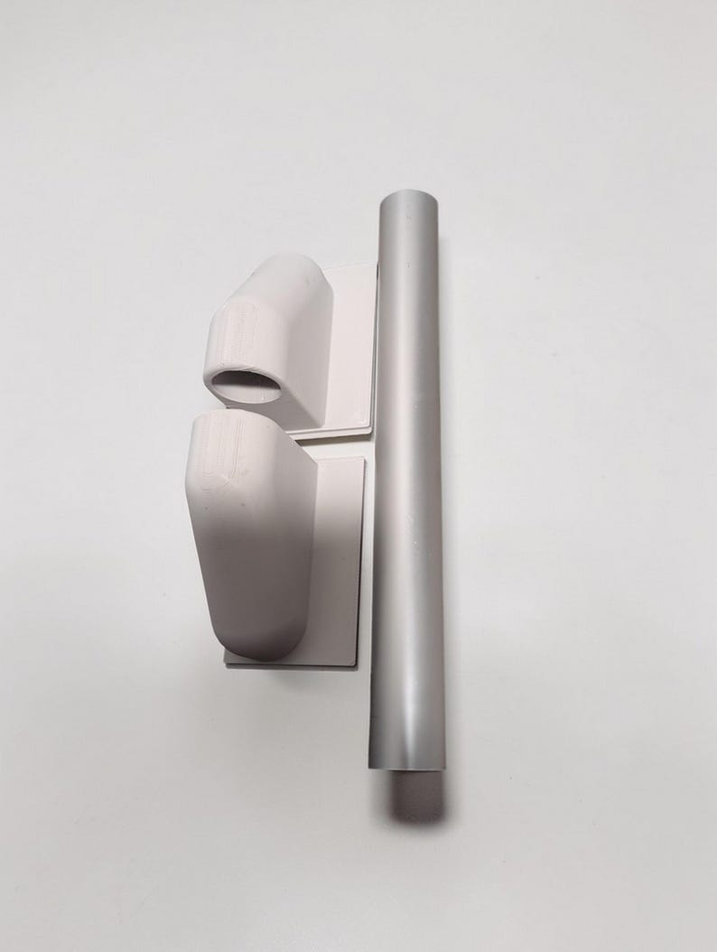 May include: A set of three-dimensional, light gray architectural components. Two angled, box-like forms are mounted on square bases. A cylindrical, vertical piece is positioned next to them. The objects are against a white background.