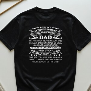 Könnte beinhalten: Schwarzes T-Shirt mit weißem Text: "I GET MY ATTITUDE FROM MY FREAKING AWESOME DAD." Das Shirt sagt auch "AND IF YOU MESS WITH ME" und "THE BEAST IN HIM WILL AWAKE & THEY'LL NEVER FIND YOUR BODY."