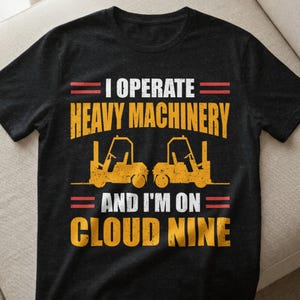 Könnte beinhalten: Schwarzes T-Shirt mit dem Text "I OPERATE HEAVY MACHINERY AND I'M ON CLOUD NINE" in Weiß und Gelb. Unter den Worten "HEAVY MACHINERY" sind zwei gelbe Gabelstapler-Illustrationen abgebildet.