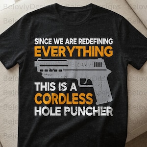 Könnte beinhalten: Schwarzes T-Shirt mit einer Pistolen-Grafik und dem Text "SINCE WE ARE REDEFINING EVERYTHING THIS IS A CORDLESS HOLE PUNCHER" in Weiß und Orange. Das Shirt besteht aus einem weichen Material.