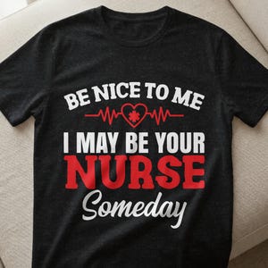 Könnte beinhalten: Schwarzes T-Shirt mit dem Text "BE NICE TO ME I MAY BE YOUR NURSE Someday" in Weiß und Rot. Das Design beinhaltet ein rotes Herz mit einem medizinischen Symbol und einer Herzschlaglinie. Ein lässiges T-Shirt für Krankenschwestern.