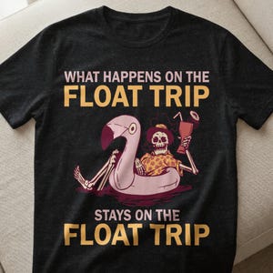 Puede incluir: Camiseta gris oscuro con el texto amarillo "WHAT HAPPENS ON THE FLOAT TRIP STAYS ON THE FLOAT TRIP". El gráfico muestra un esqueleto en un flotador de flamenco sosteniendo una bebida.
