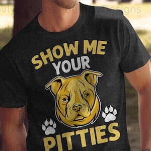Pode incluir: Camiseta cinza escuro com o texto "SHOW ME YOUR PITTIES" em amarelo e branco. A camiseta apresenta uma ilustração amarela e preta da cabeça de um pit bull e duas pegadas.