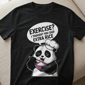 Puede incluir: Camiseta gris oscuro con un panda de dibujos animados con un gorro de chef, comiendo arroz de un cuenco rosa. Un bocadillo sobre el panda dice: "EXERCISE? I THOUGHT YOU SAID EXTRA RICE."
