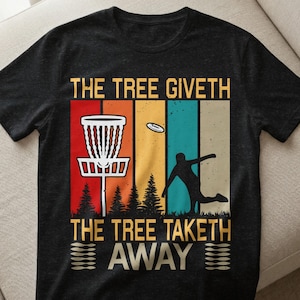 Könnte beinhalten: Dunkelgraues T-Shirt mit einem farbenfrohen Design für Disc Golf. Das Design zeigt einen Disc-Golf-Korb, eine fliegende Scheibe, eine Silhouette einer Person, die eine Scheibe wirft, und den Text "THE TREE GIVETH, THE TREE TAKETH AWAY".