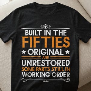Puede incluir: Camiseta negra con el texto "BUILT IN THE FIFTIES ORIGINAL AND UNRESTORED SOME PARTS STILL IN WORKING ORDER" en letras naranjas y blancas. La camiseta tiene cuello redondo y mangas cortas.