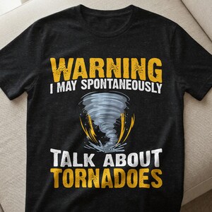 May include: Black t-shirt with the text "WARNING I MAY SPONTANEOUSLY TALK ABOUT TORNADOES" in yellow and white. A graphic of a gray tornado is in the center of the shirt, with yellow lightning bolts emanating from the base.