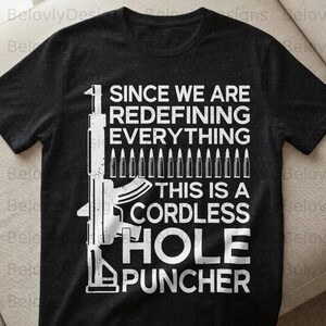 May include: Black t-shirt with a white graphic of a rifle and bullets, along with the text "SINCE WE ARE REDEFINING EVERYTHING THIS IS A CORDLESS HOLE PUNCHER."