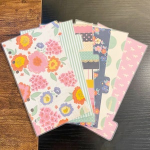 May include: A set of eight colorful patterned dividers for a planner or journal. The dividers feature floral, striped, polka dot, and horse designs.