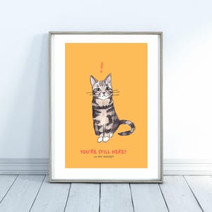 Puede incluir: Impresión artística enmarcada con una ilustración en acuarela de un gato atigrado sobre un fondo amarillo. El gato está sentado erguido con un signo de exclamación sobre su cabeza. El texto en la parte inferior dice: "YOU'RE STILL HERE? IN MY HOUSE?"