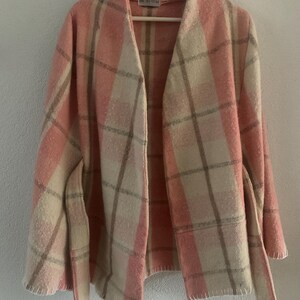 Puede incluir: Una chaqueta de manga larga abierta por delante con un patr&oacute;n de cuadros en rosa, crema y beige. La prenda tiene un cuello ancho, un cintur&oacute;n para anudar a la cintura y costuras visibles a lo largo del dobladillo. Una etiqueta est&aacute; cosida.