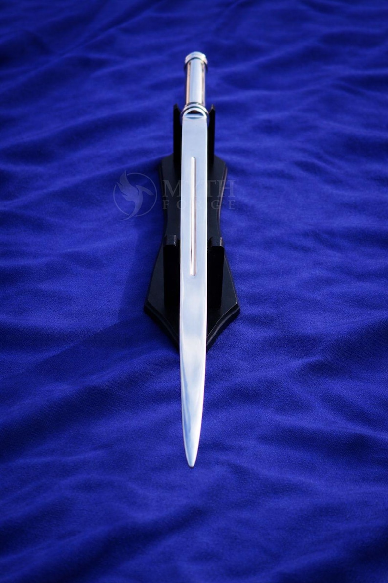 May include: A silver-colored sword with a polished blade, displayed on a black stand against a blue background. The sword has a straight, double-edged blade and a silver handle. The stand is angled.