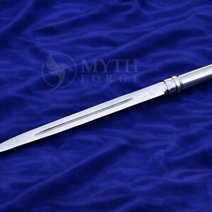 May include: A polished, silver dagger with a long, slender blade and a detailed handle. The dagger is displayed against a deep blue background. The text "MYTH FORGE" is visible in the upper right corner.