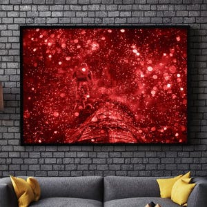 May include: A framed art print depicting an astronaut floating in a red, starry space. The astronaut is in a spacesuit, and the background is filled with bokeh-like light effects. The artwork is mounted on a brick wall above a gray sofa with yellow pillows.