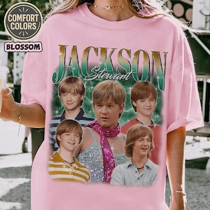 May include: A pink Comfort Colors t-shirt featuring a graphic of the name "Jackson Stewart" in a vintage style, with multiple images of a person. The shirt has the word "Blossom" printed on it.