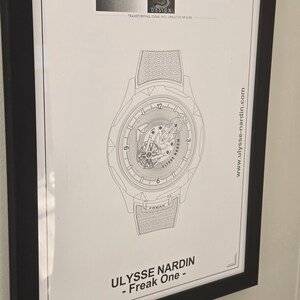May include: Framed black and white print of a watch design. The watch illustration features intricate details, including the text "ULYSSE NARDIN - Freak One." The print also includes the website address www.ulysse-nardin.com and the "CLASS S DESIGN" logo.