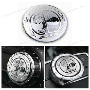 Puede incluir: Un emblema AMG plateado con las palabras "AFFALTERBACH" y "AMG" en un diseño circular. El emblema presenta un árbol y un motor estilizado. Imágenes adicionales muestran el emblema en los mandos del coche.