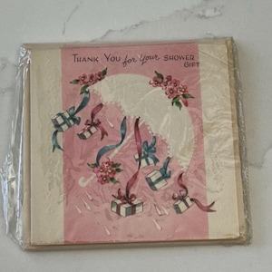 Peut inclure: Un lot de cartes de remerciement vintage pour un cadeau de fête, enveloppées dans du plastique transparent. Les cartes ont un fond rose avec des illustrations de cadeaux, de rubans et de fleurs. Le texte dit "Thank You for your Shower Gift."