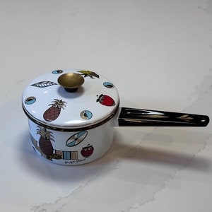 May include: White enamel saucepan with a lid, featuring a black handle and a brass knob. The pot is decorated with colorful illustrations of pineapples, strawberries, and other fruit. The text "Georges Briard" is printed on the side.