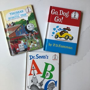 May include: Three children's books are displayed. The top left book is titled "Thomas and the School Trip" with an illustration of a train. The top right book is "Go, Dog. Go!" with a dog driving a yellow car. The bottom book is "Dr. Seuss's ABC".