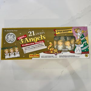 May include: A box of GE 21 Lights, 3 Angels Collector Series Christmas lights. The box features images of angel figurines and a Christmas tree. The text on the box reads "Three little angels from Hallmark add a heavenly light to your holiday."