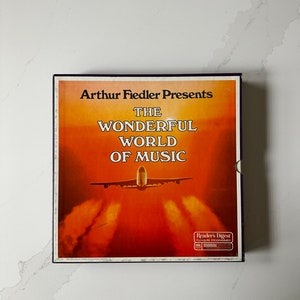 May include: A vintage record album titled "Arthur Fiedler Presents The Wonderful World of Music." The album cover shows an aeroplane taking off against a sunset backdrop. The Reader's Digest logo is visible.