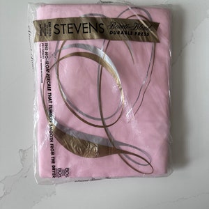 May include: A pink Stevens Beauty-Blend fitted sheet set in its original packaging. The packaging includes text that reads "Durable Press" and "The No-Iron Percale That Tumbles Smooth From The Dryer". The sheet set is for a king-sized standard mattress.