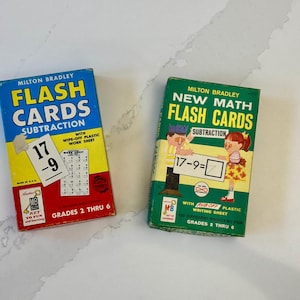 May include: Two vintage Milton Bradley flash card sets for subtraction. One is blue, yellow, and red, and the other is green and yellow. Both sets are labeled for grades 2 through 6 and feature wipe-off plastic work sheets.